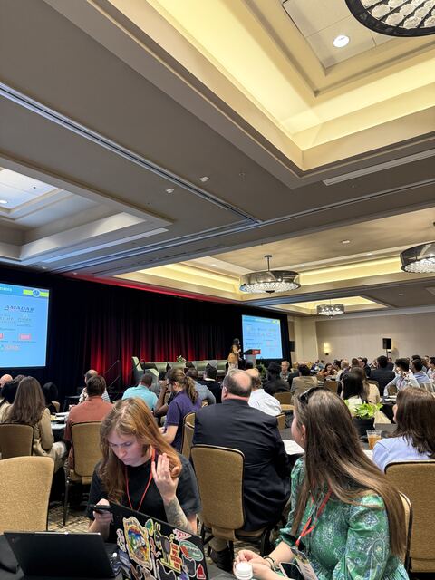 A packed conference ballroom during a presentation session