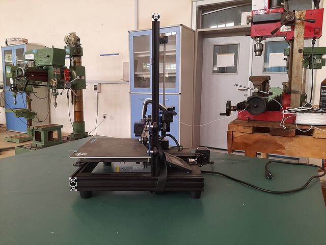 Side view of the printer on a workbench among drill presses and milling machines
